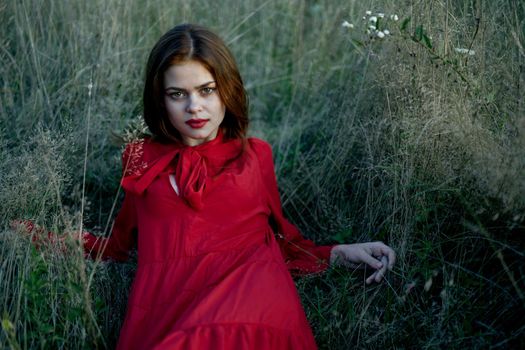 woman lies on the grass in a red dress landscape fashion. High quality photo