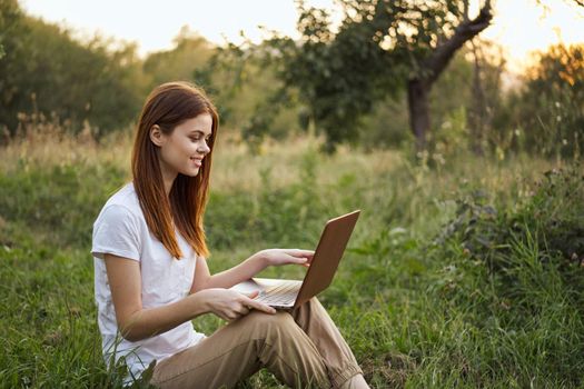 women outdoors in field with laptop leisure technology freedom. High quality photo