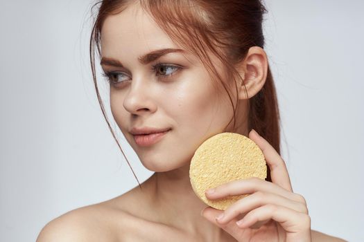 woman with a sponge in her hands bare shoulders skin care closeup. High quality photo