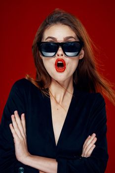 cheerful fashionable woman wearing sunglasses red lips posing red background. High quality photo