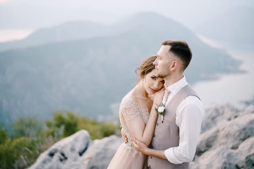 Groom embraces bride on the mountain. Portrait. High quality photo
