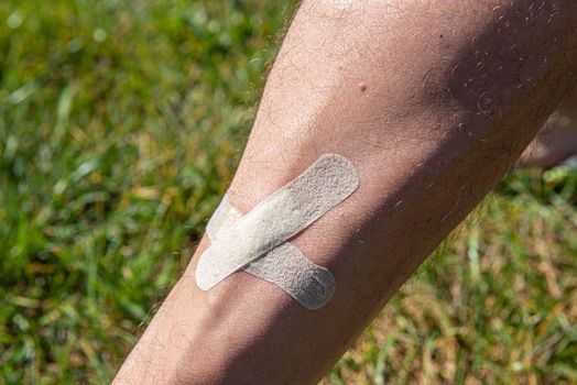 male shin wound sealed by adhesive plaster close up.