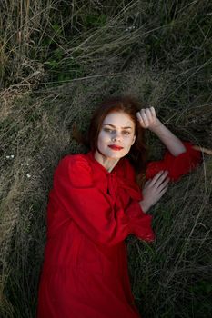 pretty woman in red dress lies on the grass posing top view. High quality photo