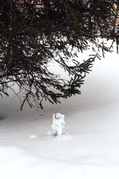 Statuette of an astronaut confidently explores alien planet's surface. Cold planet covered with snow. Copy space.