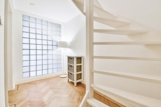 White hallway with wooden stairway leading to second floor of modern luxury apartment with minimalist interior design