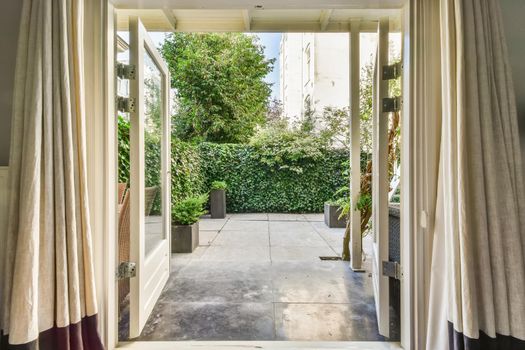 Open door with full length curtains leading to the courtyard of the house
