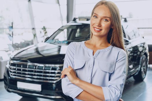 Young woman checking out a new car she is going to buy in car salon