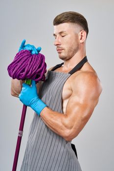 man in apron with mop in hand posing housework. High quality photo