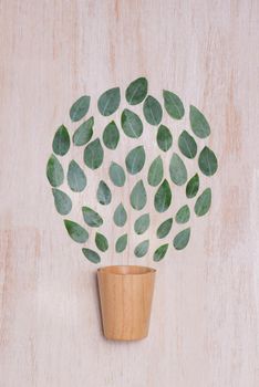 Flat lay of a wooden cup with leaves on table.