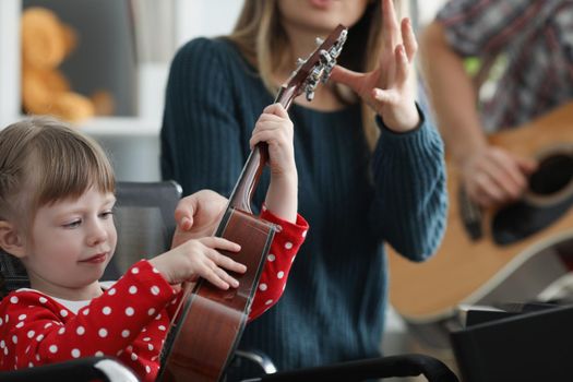 Portrait of mother take musical instrument from daughter hands to show how to play. Parent and daughter form home band. Music, creativity, talent concept