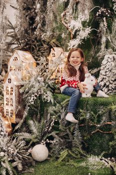 beautiful girl poses for the camera in a beautiful christmas decoration with a lot of trees under a snow on background