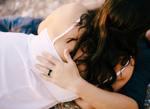 Man and woman hugging while lying on the gravel path in the park. High quality photo