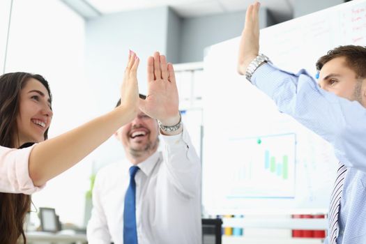 Portrait of team clapping hands together giving high five to celebrate finished business project. Successful teamwork in company office. Success concept