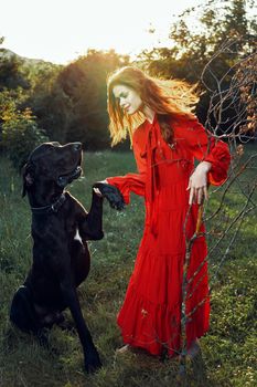 cute woman in red dress playing with dog outdoors friendship. High quality photo