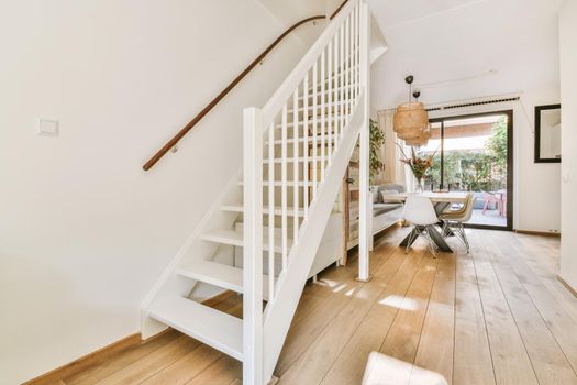 White hallway with wooden stairway leading to second floor of modern luxury apartment with minimalist interior design