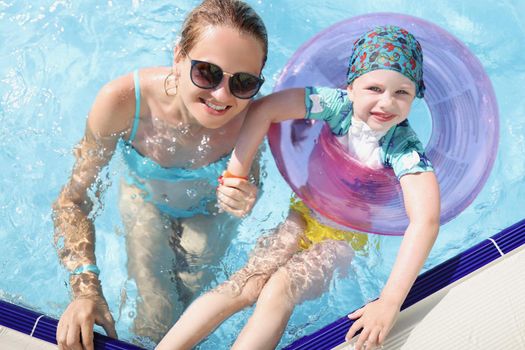 Top view of mother and daughter swimming in pool enjoy summer holiday. Smiling and happy parent and child on resort. Summer, childhood, parenthood concept