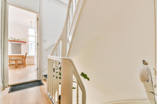 White spiral stairway connecting levels of contemporary house with wooden floor and white walls