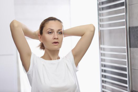 Portrait of young woman looking in mirror at herself in bathroom, pretending shes beautiful, morning routine. Good morning, wellness, beauty ritual concept