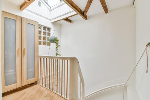 White spiral stairway connecting levels of contemporary house with wooden floor and white walls