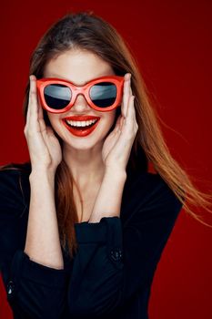 pretty woman wearing sunglasses fashion posing hairstyle red background. High quality photo