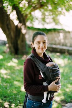 Smiling mother with baby in a sling. Close-up. High quality photo