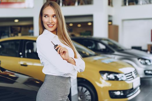Young happy woman buyer/seller near the car with keys in hand close up