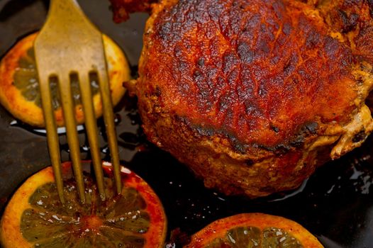 pork chop seared on iron skillet with lemon and spices seasoning