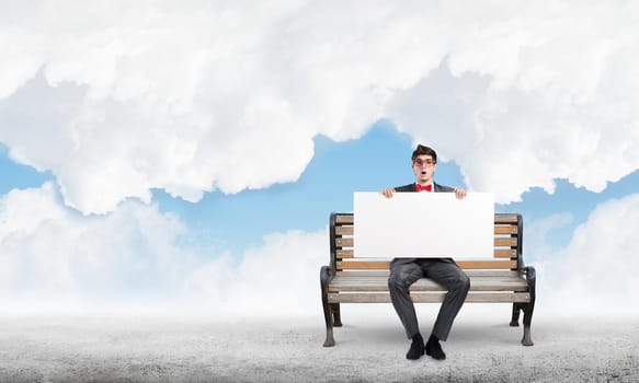Young businessman holds a large white banner. sits on the bench