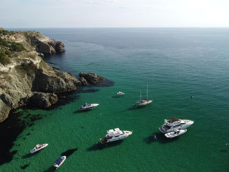 Sea landscape with rocky coastline on sunset time with cloudy sky. Yachts in the Sea on a background of rocky shores. The concept of perfect place for summer travel and rest.