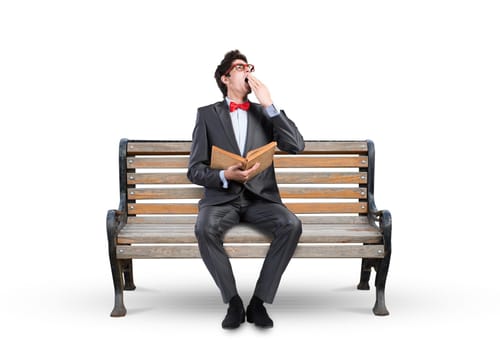 Student sits on a bench, holding a book. Traditional education concept
