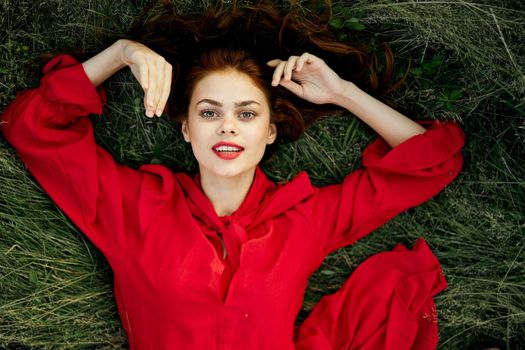woman in red dress lies on the grass top view freedom. High quality photo