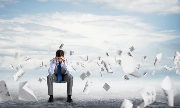 Businessman is sitting on an office chair with his head in his hands. Business stress and problems
