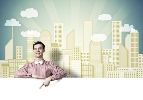 Young funny guy in checked shirt pointing with finger at blank banner