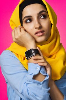 muslim woman with smart watch technology posing pink background. High quality photo