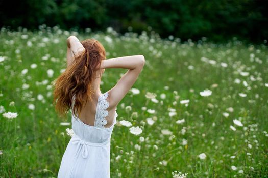 Woman in white dress in a field of flowers walk freedom. High quality photo