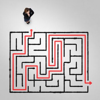 Top view of puzzled businesswoman looking at drawn maze on floor