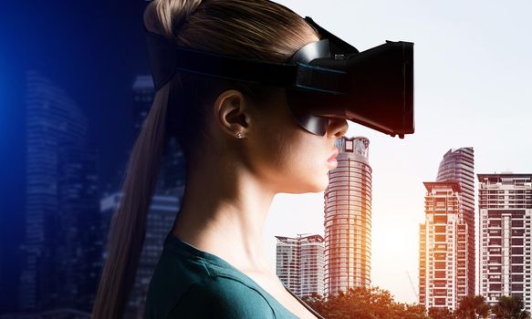 A young attractive woman looks at the cityscape through VR glasses.