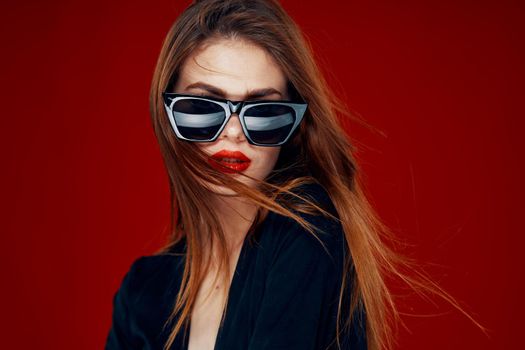 cheerful fashionable woman wearing sunglasses red lips posing red background. High quality photo