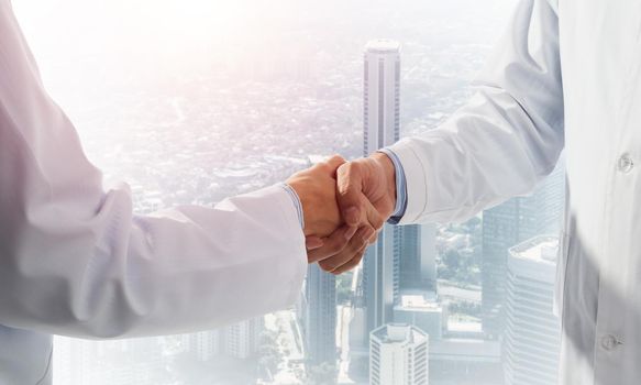 Close-up of the handshake between the two medics. Against the backdrop of the cityscape