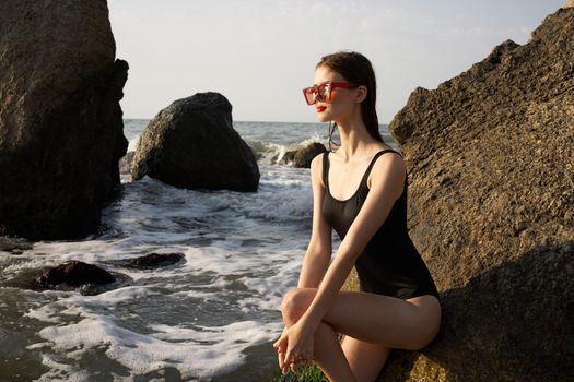 woman in black swimsuit posing near rocks ocean exotic. High quality photo