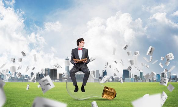 young businessman with a book. flying around papers in chaos
