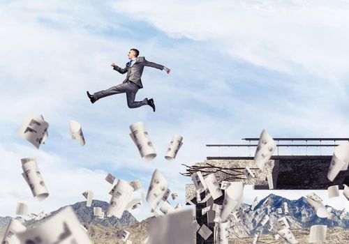 Businessman jumping over gap in bridge among flying papers as symbol of overcoming challenges. Skyscape and nature view on background. 3D rendering.