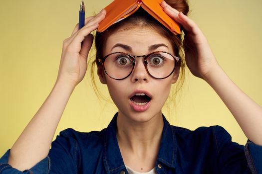 woman student with glasses notepad with pen yellow background. High quality photo