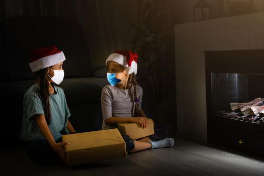 Child in a Santa hat wearing medical face mask with Christmas gift box. Christmas shopping. Copy space