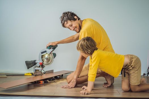 Father and son installing new wooden laminate flooring on a warm film floor. Infrared floor heating system under laminate floor.