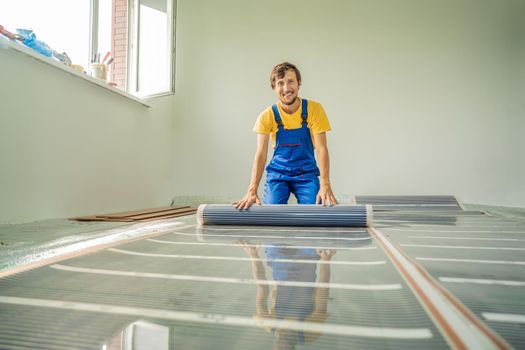 Master installs film warm floor in the room. Floor heating installation.