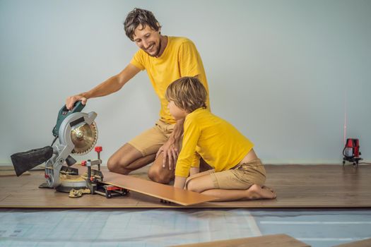 Father and son installing new wooden laminate flooring on a warm film floor. Infrared floor heating system under laminate floor.