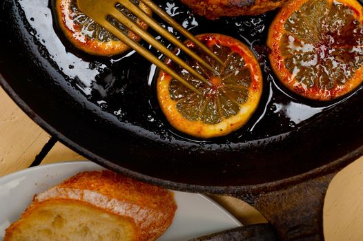 pork chop seared on iron skillet with lemon and spices seasoning