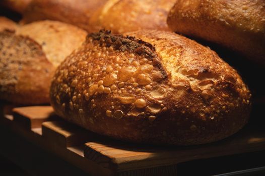 Appetizing fresh hot artisan bread. Close-up of a loaf of delicious bread on a wooden pallet.