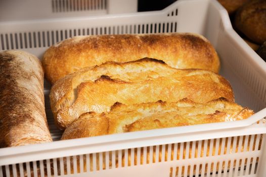 Fresh hot artisan bread in a white plastic transport box. Healthy and tasty food baked goods.